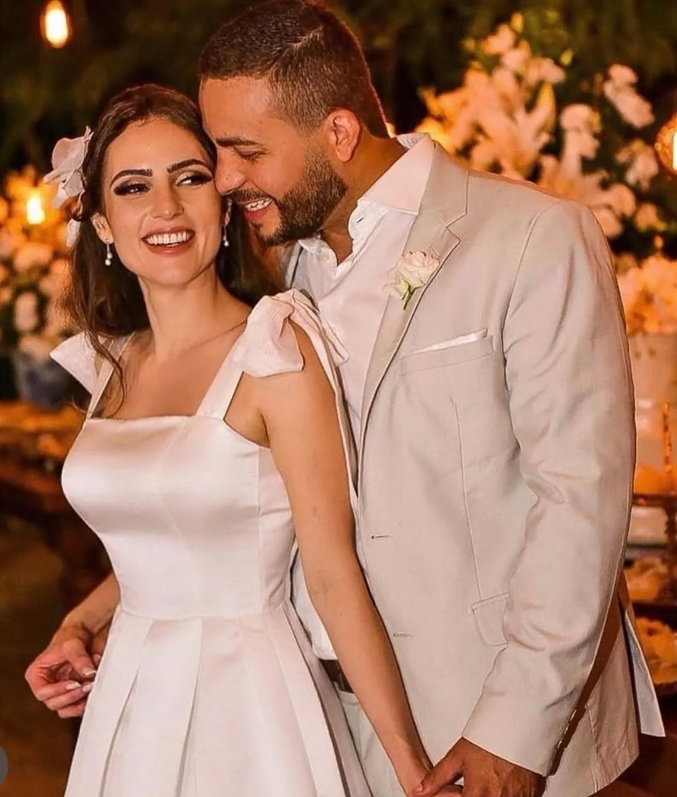 Noiva de vestido acetinado ao lado do noivo em terno claro