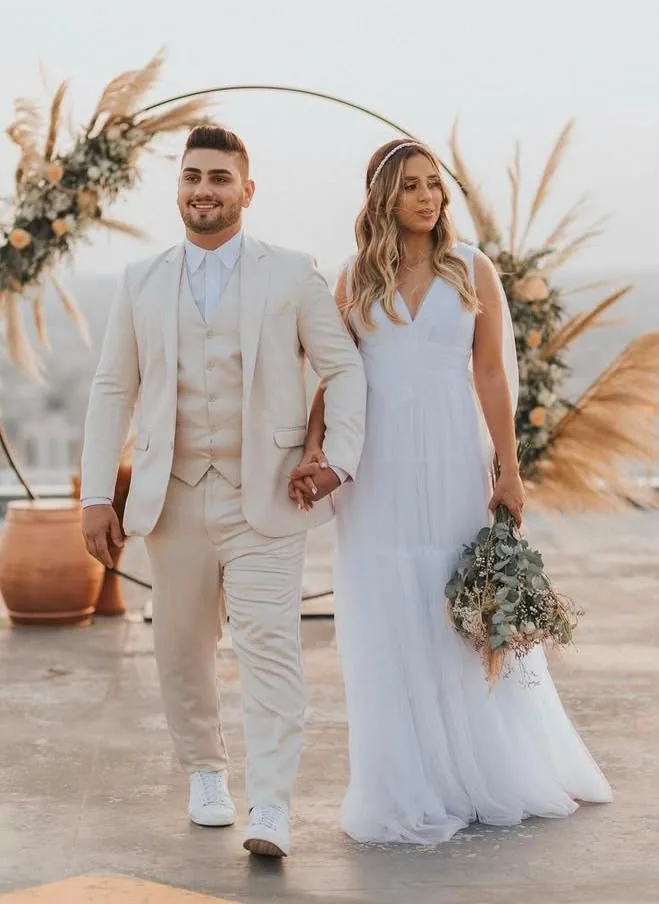 Casal sob arco de flores com vestido leve e buquê