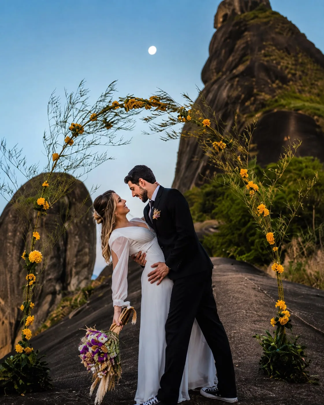 Casal sob arco de flores amarelas ao luar entre as pedras