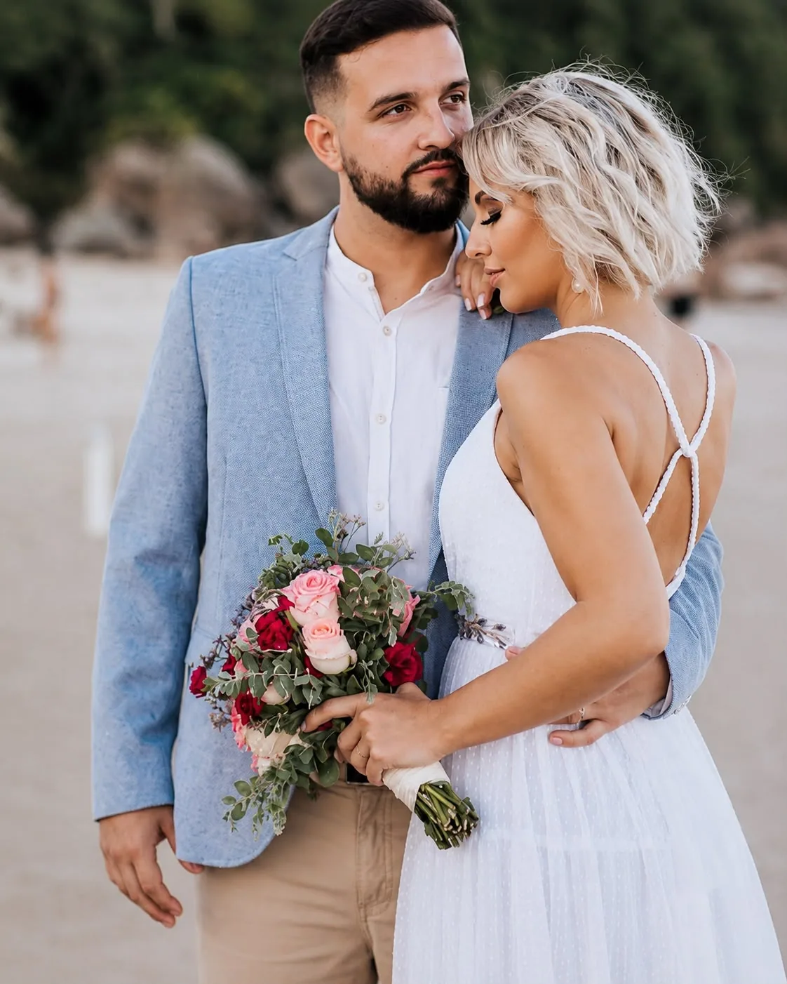 Casal abraçado com buquê colorido em ensaio ao ar livre